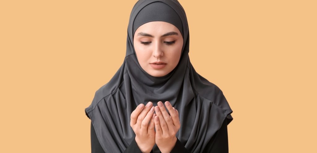 امرأة محجبة ترفع يديها بالدعاء