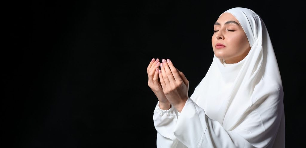 امرأة محجبة ترفع يديها بالدعاء