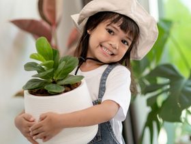 فتاة تحمل نبتة خضراء