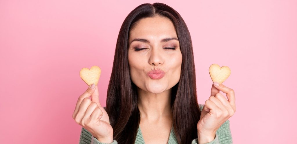 امرأة تغلق عينيها وتحمل بسكويت على شكل قلب