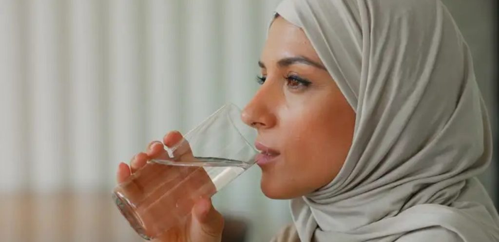 امرأة تشرب كوبًا من الماء