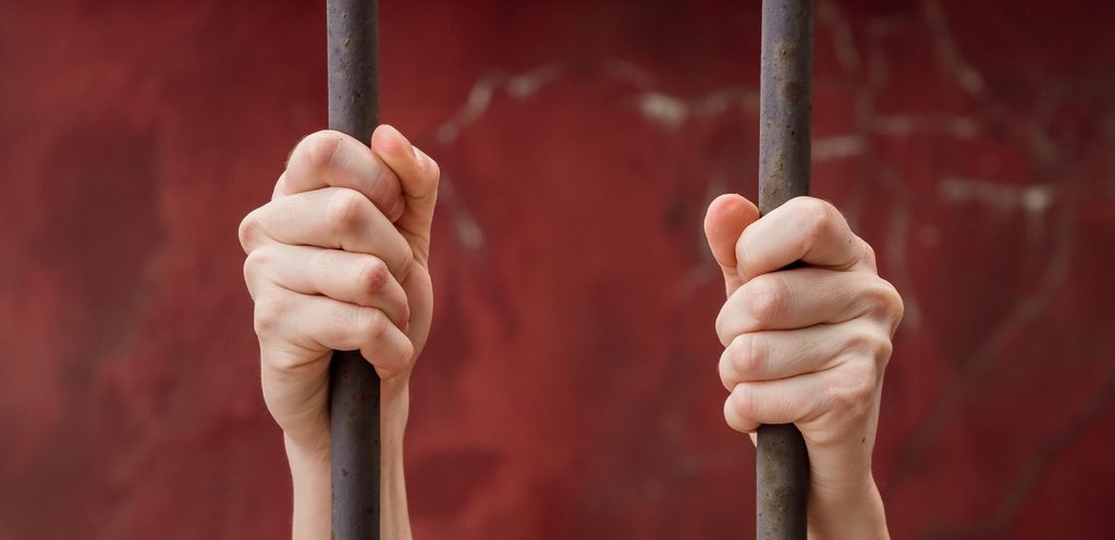 امرأة تمسك قضبان السجن