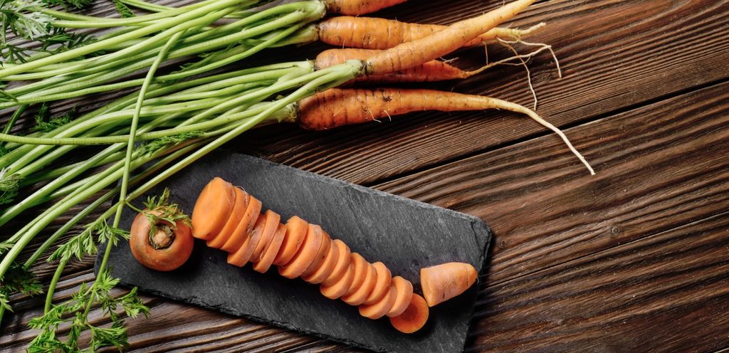 حبات من الجزر وبجانبها جزر مقطّع