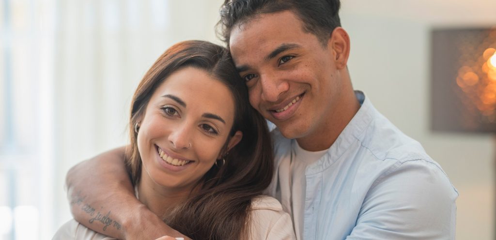 رجل يعانق شريكته وهما يضحكان
