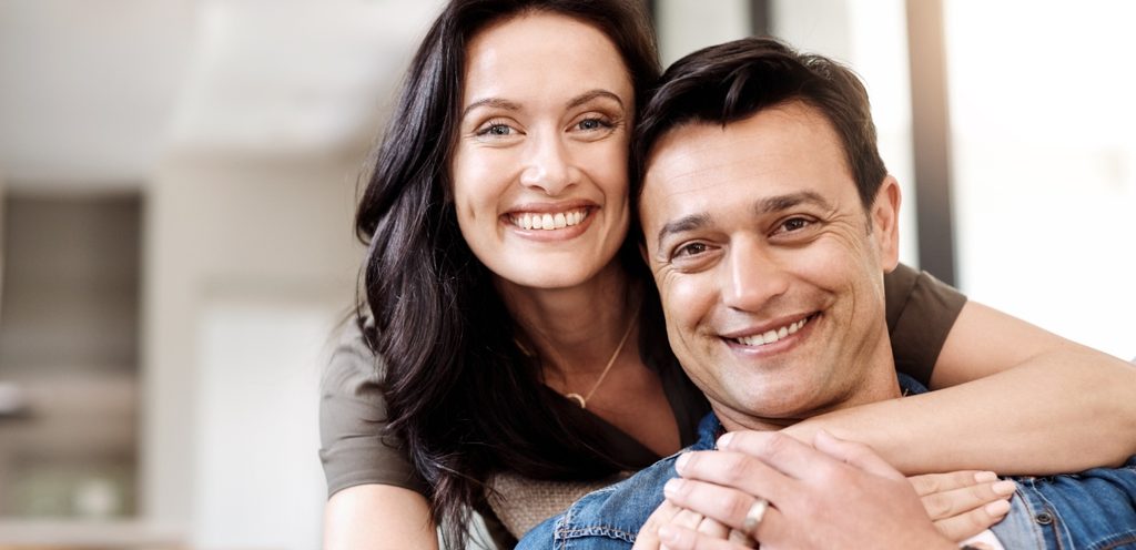 امرأة تعانق زوجها وهما مبتسمان