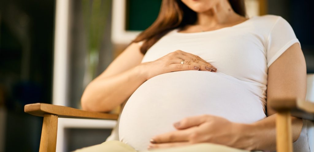 امرأة حامل تضع يديها على بطنها