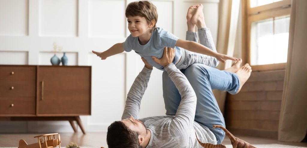 أب يحمل طفله عاليًا مستعينًا بيديه ورجليه