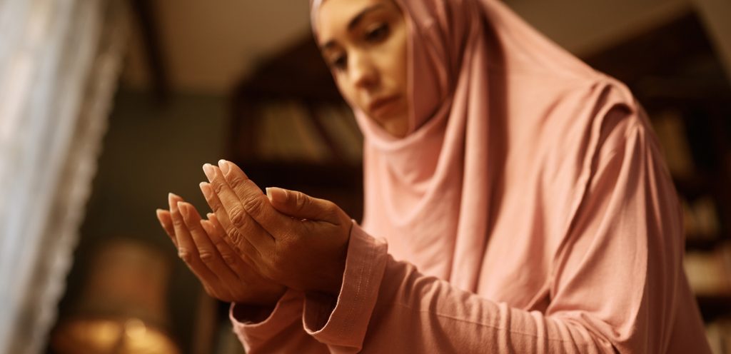 امرأة ملسمة تصلي وترفع يديها للدعاء