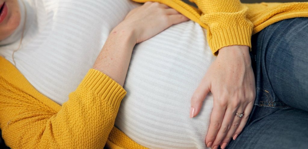 امرأة حامل تضع يديها على بطنها