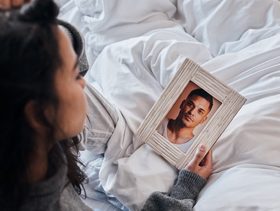 امرأة حزينة تحمل صورة زوجها وتنظر إليها