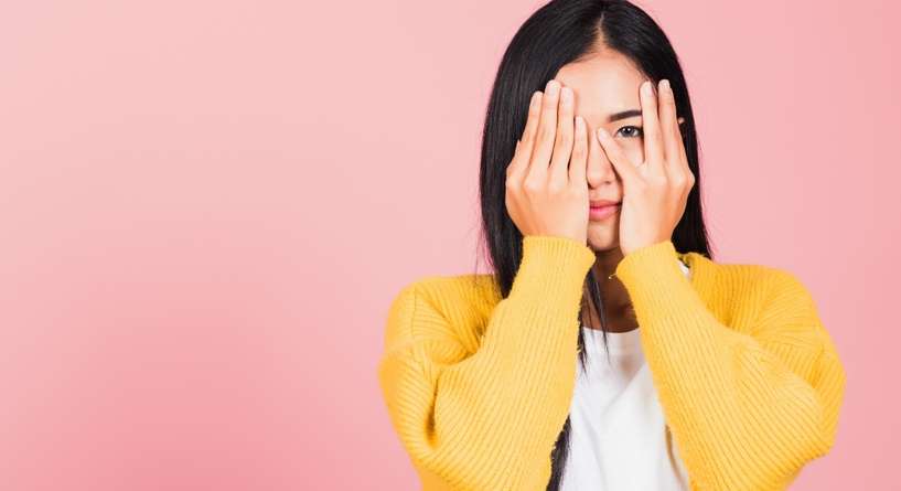 امرأة تُظهر عينها من وراء يدها