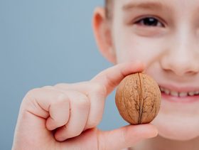 طفل يحمل بيده حبة جوز