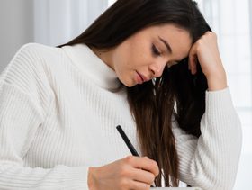 امرأة تكتب رسالة بحزن