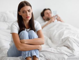 امرأة تجلس حزينة فب الفراش