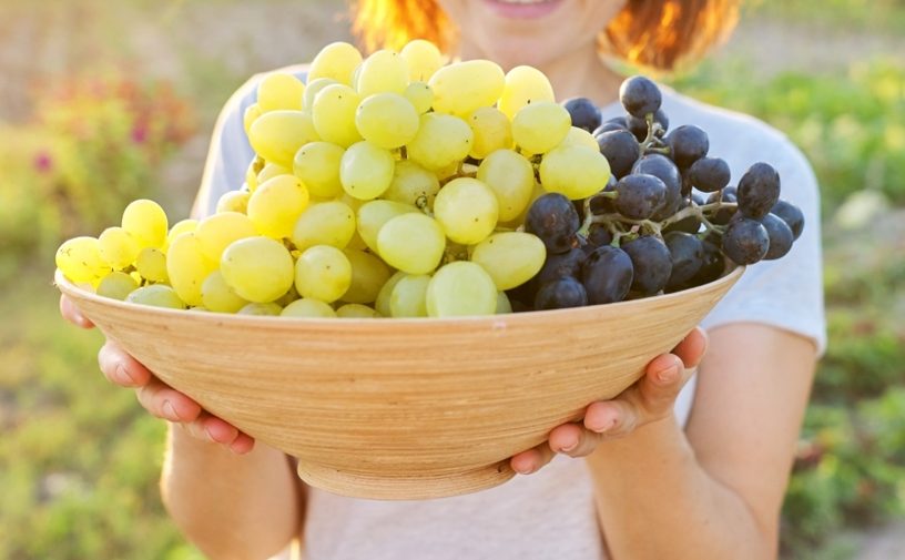 امرأة تحمل طبقًا من العنب