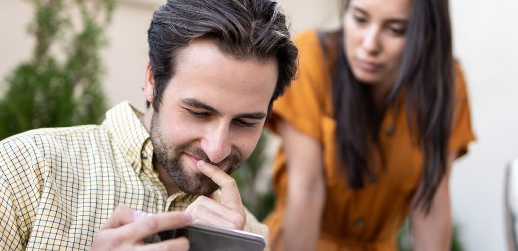 رجل يمسك هاتفه وزوجته تراقبه
