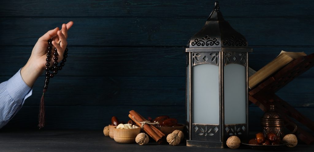 يد امرأة تمسك مسبحة وفانوس