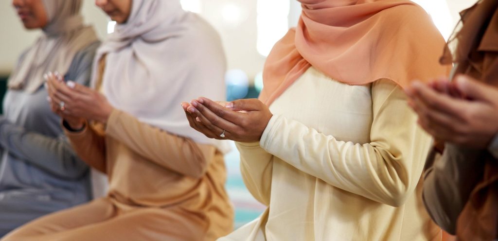 نساء مسلمات يجلسنَ على الأرض ويرفعنَ أيديهنَّ للدعاء