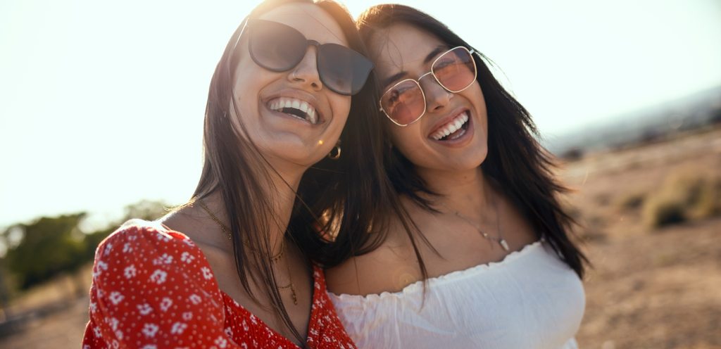 شابّتان ترتدي كّل واحدة منهما نظارات شمسية وتضحكان