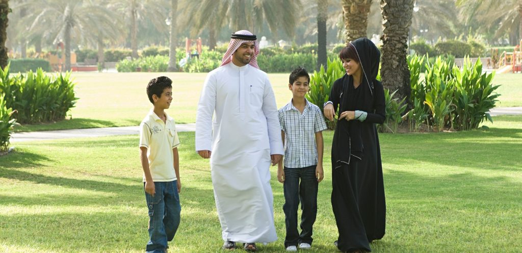 أم وأب وطفلان يتمشّون في حديقة