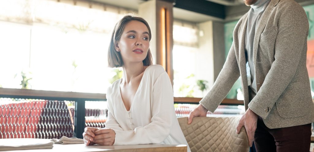 رجل يمسك الكرسي لشريكته كي تجلس