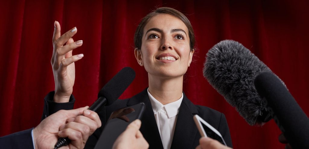 امرأة تتحدّث بسعادة وميكروفونات موجّهة نحوها