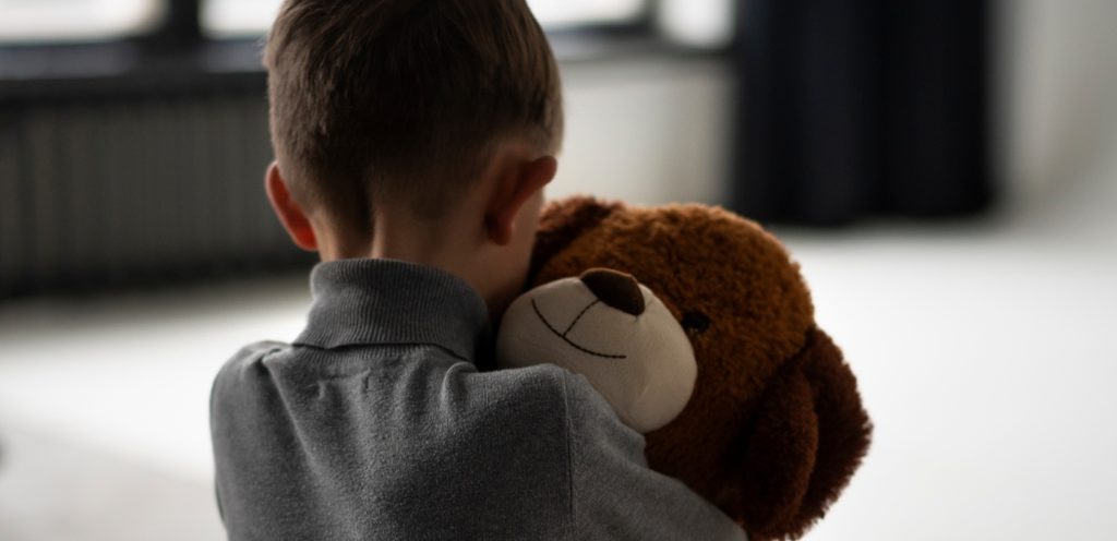 طفل حزين يعانق دميته
