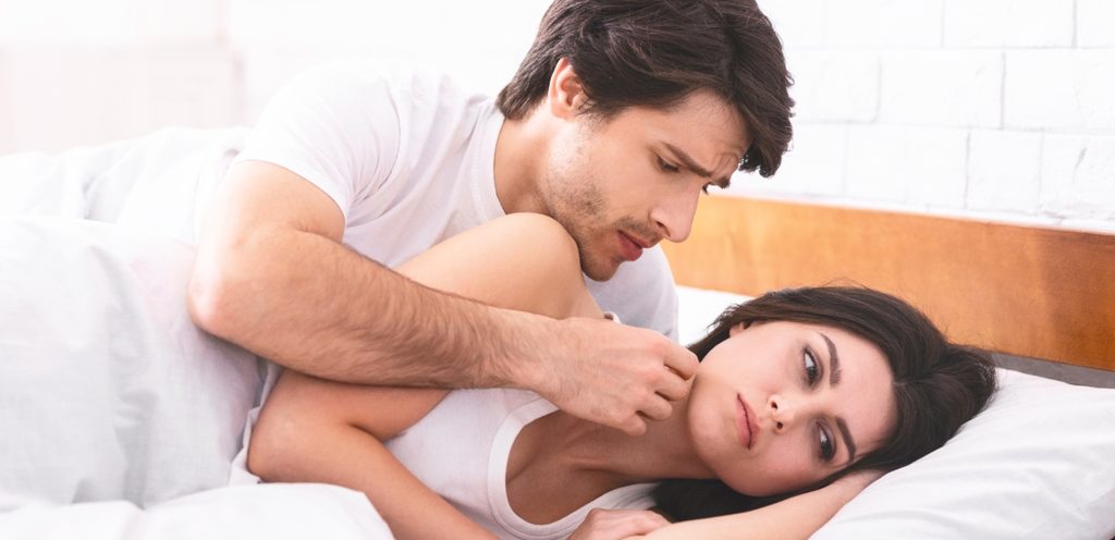 رجل يحاول التقرّب من امرأة في السرير وهي تتجاهله