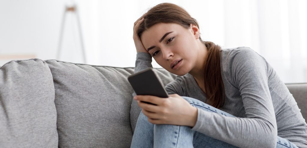 امرأة حزينة تنظر إلى هاتفها