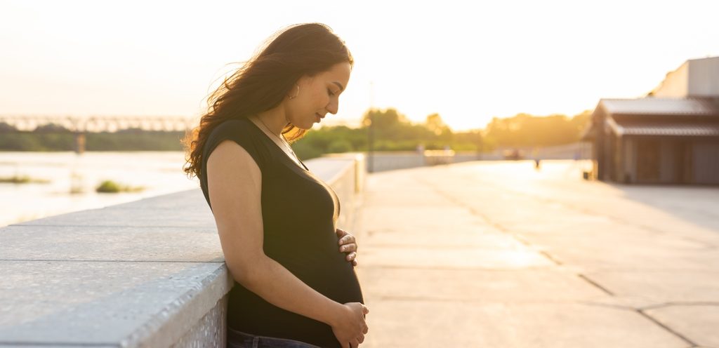 امرأة حامل تقف مستندة على الحائط