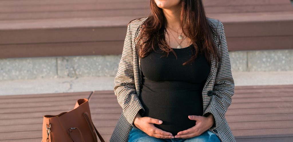 امرأة حامل تجلس على مقعد خشبي