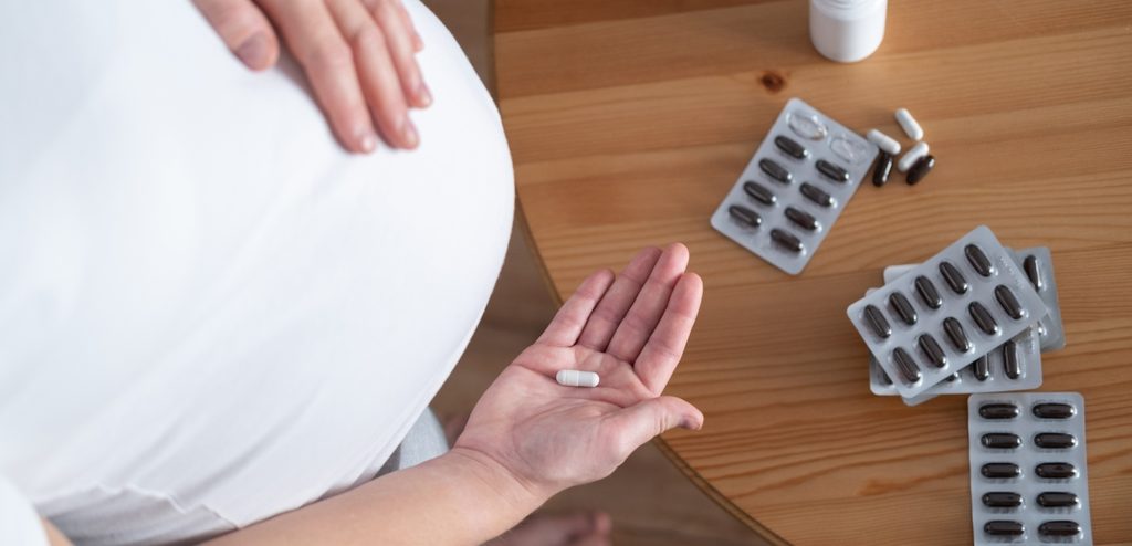 امرأة حامل تمسك حبة من الدواء