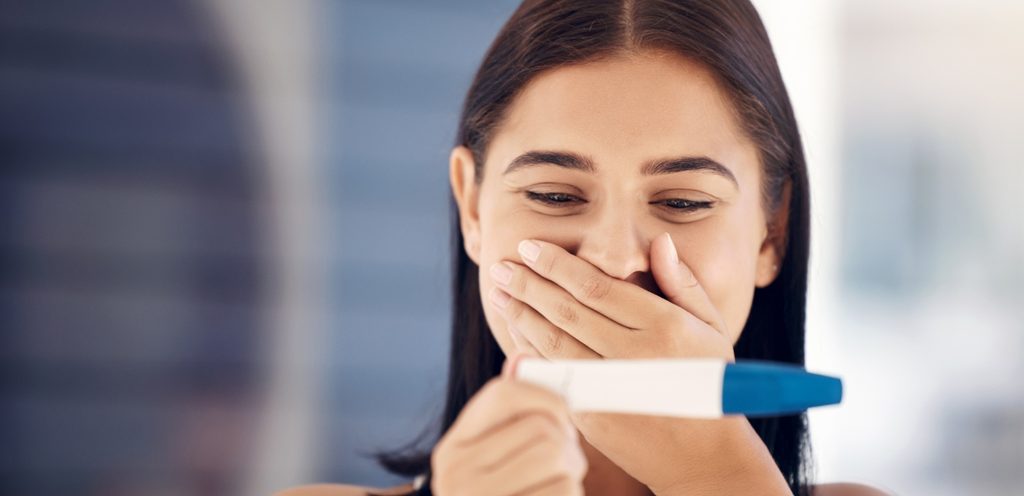 امرأة تمسك اختبار حمل متفاجئة