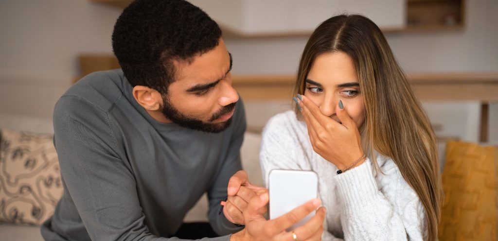 رجل يمسك هاتف ويُريه لزوجته