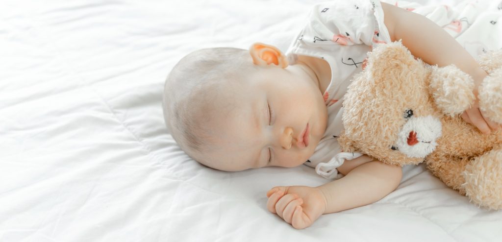 طفل رضيع نائم ويعانق دميته