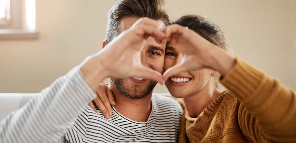 زوجان سعيدان يصنعان شكل قلب بأيديهما