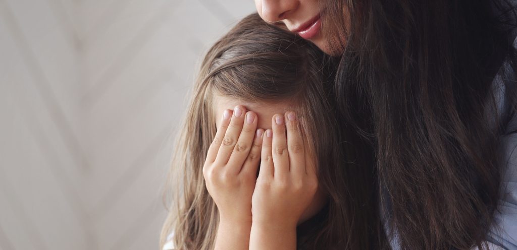 طفلة حزينة ووالدتها تعانقها