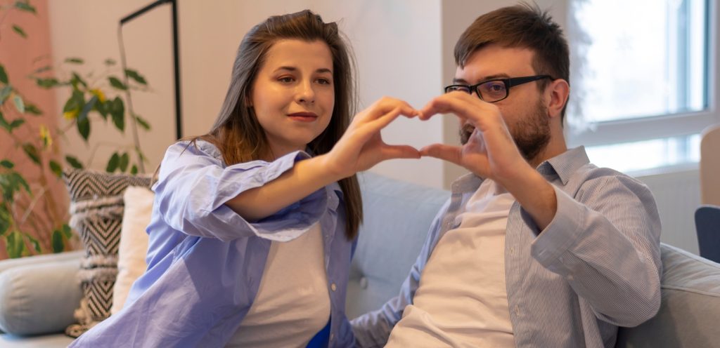 زوجان سعيدان يصنعان شكل قلب بأيديهما