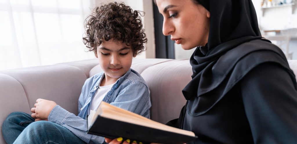 امرأة تمسك كتابًا وطفلها بجانبها