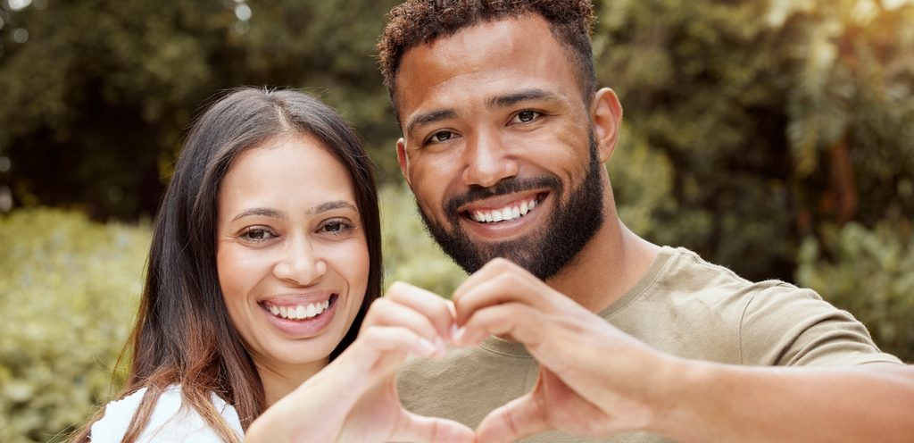 امرأة ورجل سعيدان يصنعان قلبًا بيديهما