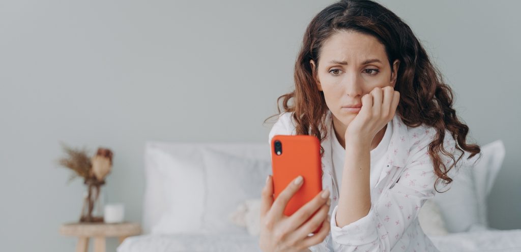 امرأة حزينة تنظر إلى هاتفها