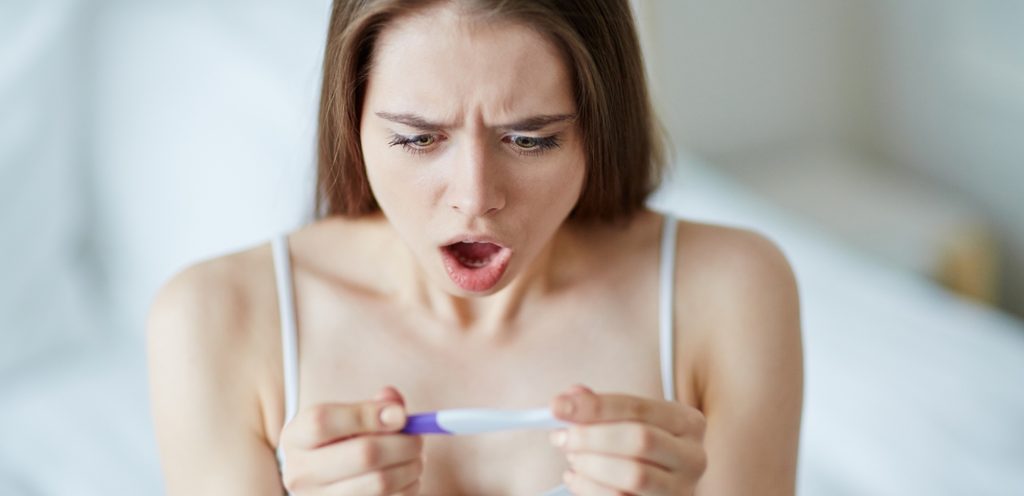 امرأة تمسك اختبار حمل متفاجئة