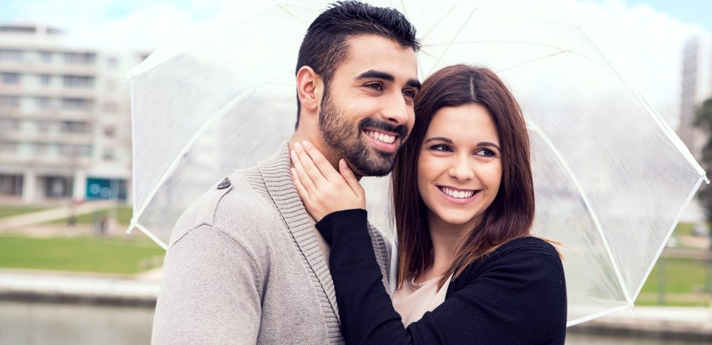 امرأة ورجل سعيدان يمسكان مظلّة