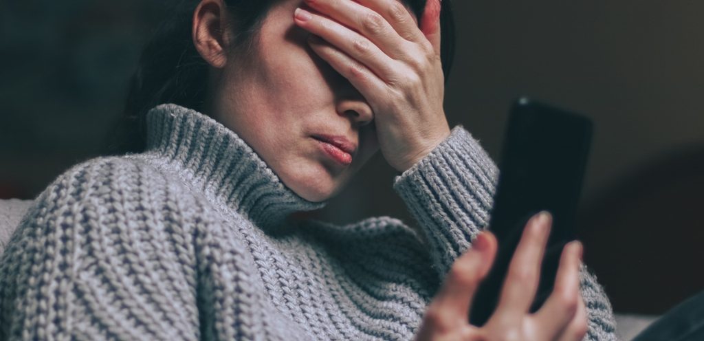 امرأة حزينة تنظر إلى هاتفها