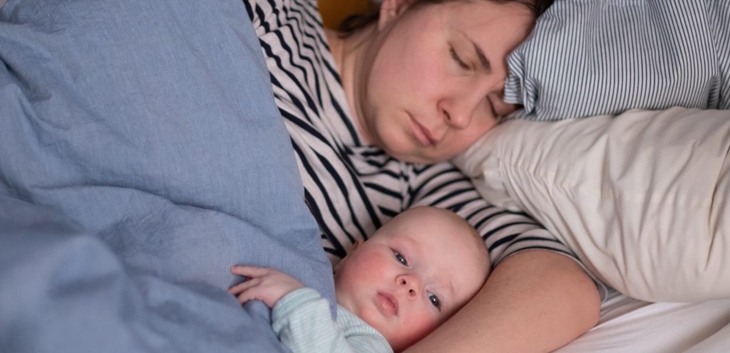 أم وطفلها الرضيع نائمان في السرير