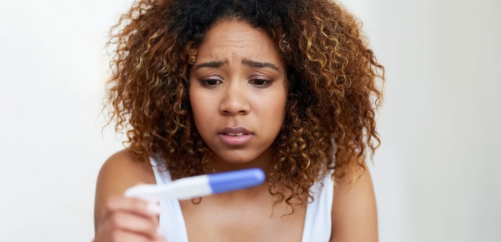 امرأة تمسك اختبار حمل متفاجئة