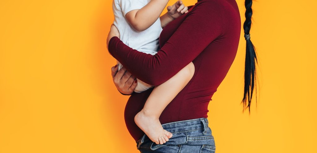 امرأة حامل تحمل طفلها