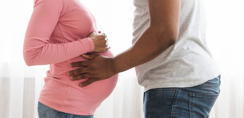 امرأة حامل وزوجها يضع يديه على بطنها
