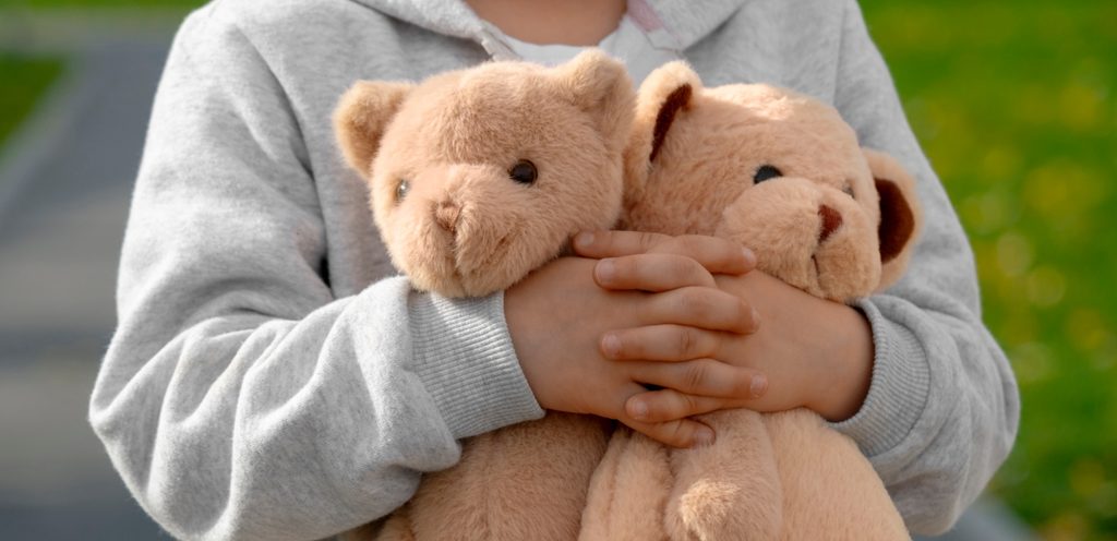 طفل يحمل دميتين