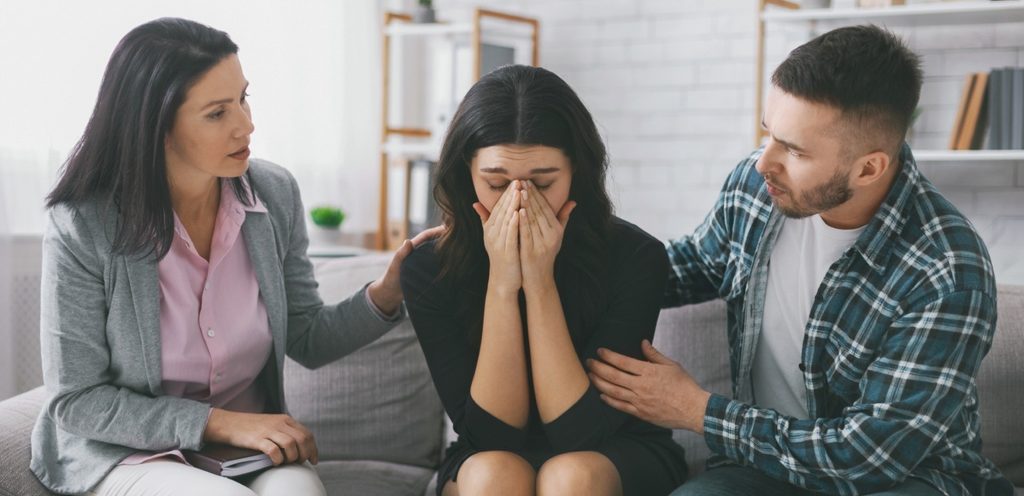 امرأة حزينة وبجانبها رجل وامرأة